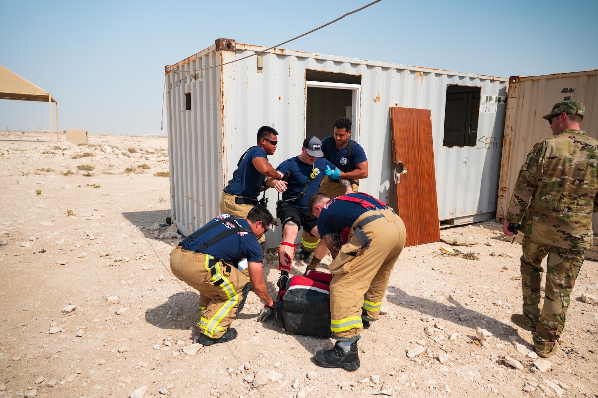 U.S. Air Force firefighters from the 379th Expeditionary Civil Engineer Squadron assist Senior Airman Colton Kelly (center) a simulated casualty during an exercise Aug. 24, 2022 at Al Udeid Air Base, Qatar. The firefighters were evaluated on their emergency response to Kelly’s simulated leg wound, caused by stepping on explosive ordnance. (U.S. Air Force photo by Staff Sgt. Dana Tourtellotte)
