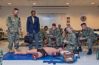 220829-N-DQ752-0068 JOINT BASE SAN ANTONIO FT. SAM HOUSTON, Texas (Aug. 29, 2022) Dr. Jonathan Woodson, President of the Uniformed Services University, observes students in the Hospital Corpsman Basic (HCB) program practicing tactical combat casualty care during a tour of the HCB classroom facilities at the Medical Education and Training Campus (METC). Navy Medicine Training Support Center is the Navy component command that provides administrative and operational contro