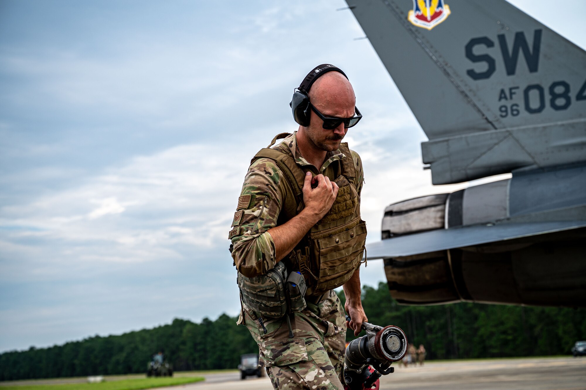 A photo of an Airman carrying a hose.