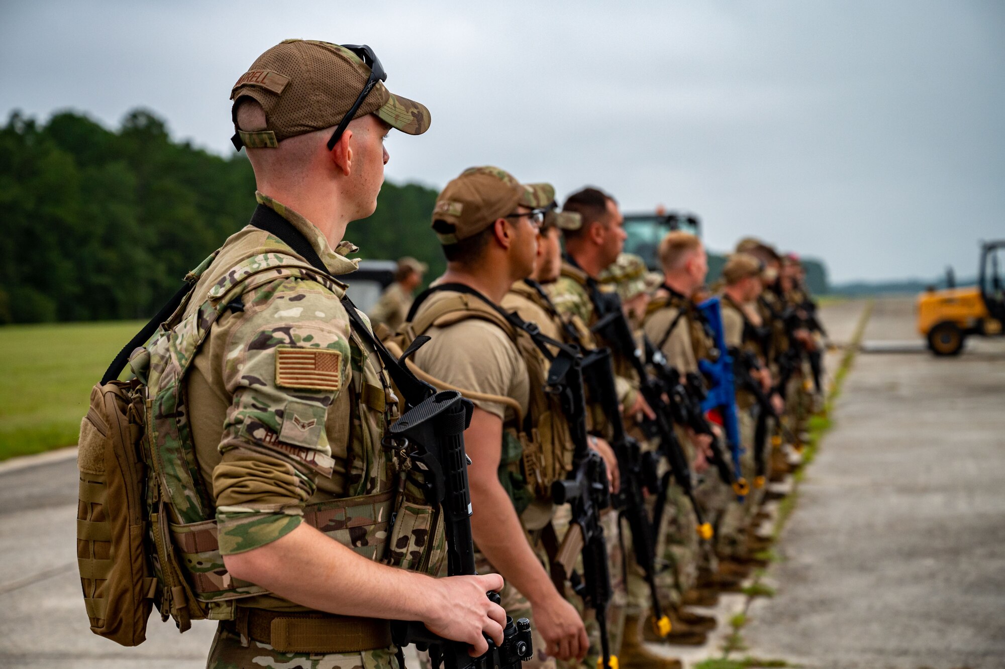 A photo of Airmen standing in a line holding weapons.