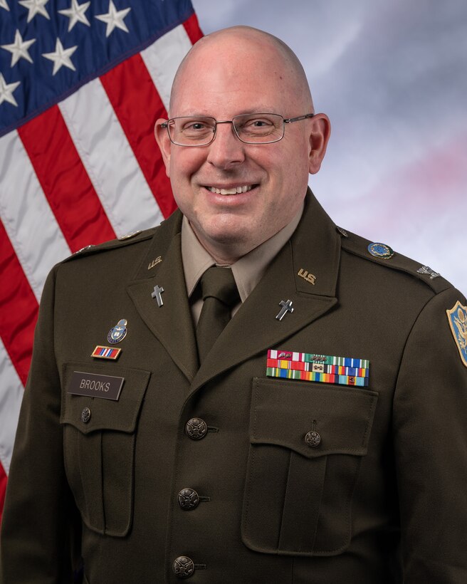 New DLA Chaplain poses in front of an American flag.