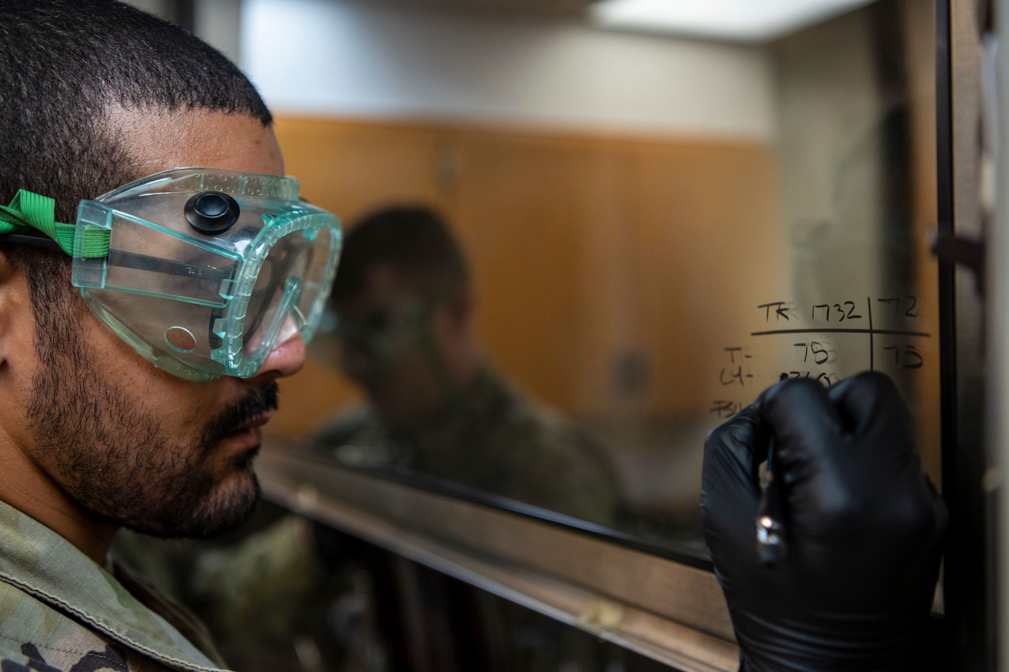 a man wearing large green goggles works in a chemical environment
