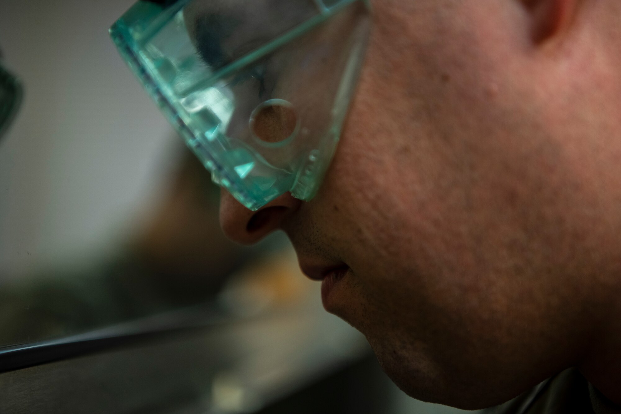 a man is wearing large green glasses working in a chemical environment