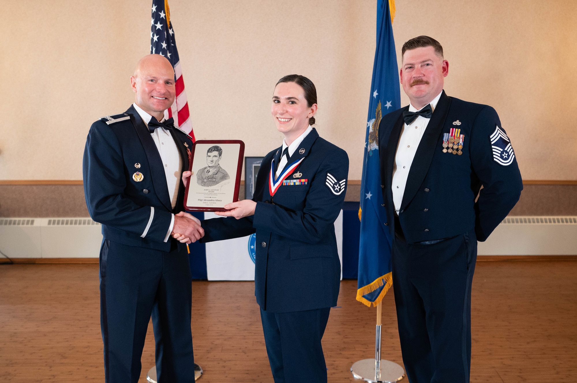 Three Airmen pose for a photo with an award.