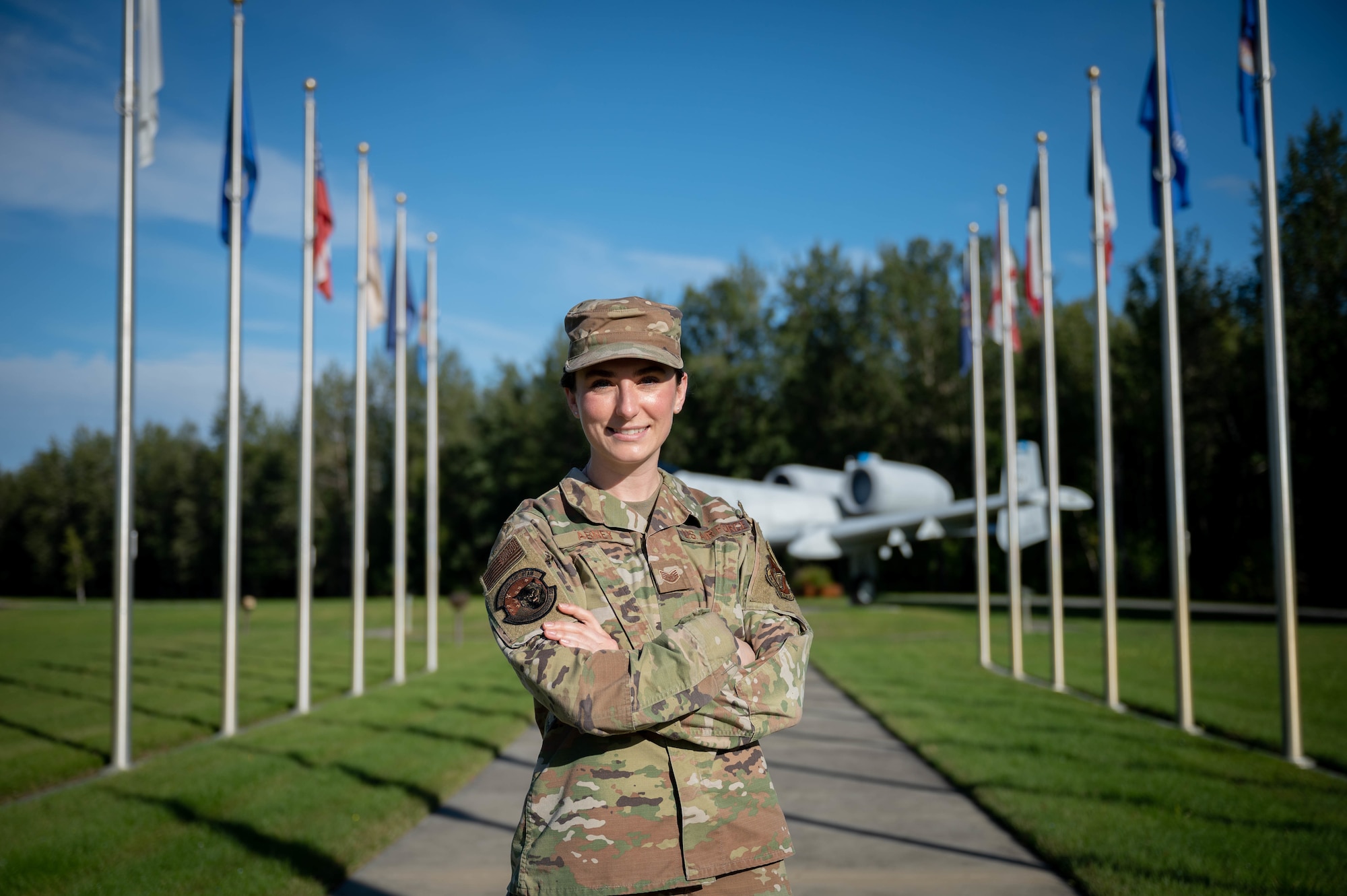 An Airman poses for a photo in the middle of two rows of flags.