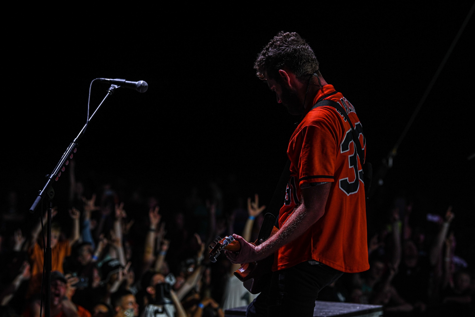Seth Morrison from the band Skillet plays guitar on stage in front on crowd.