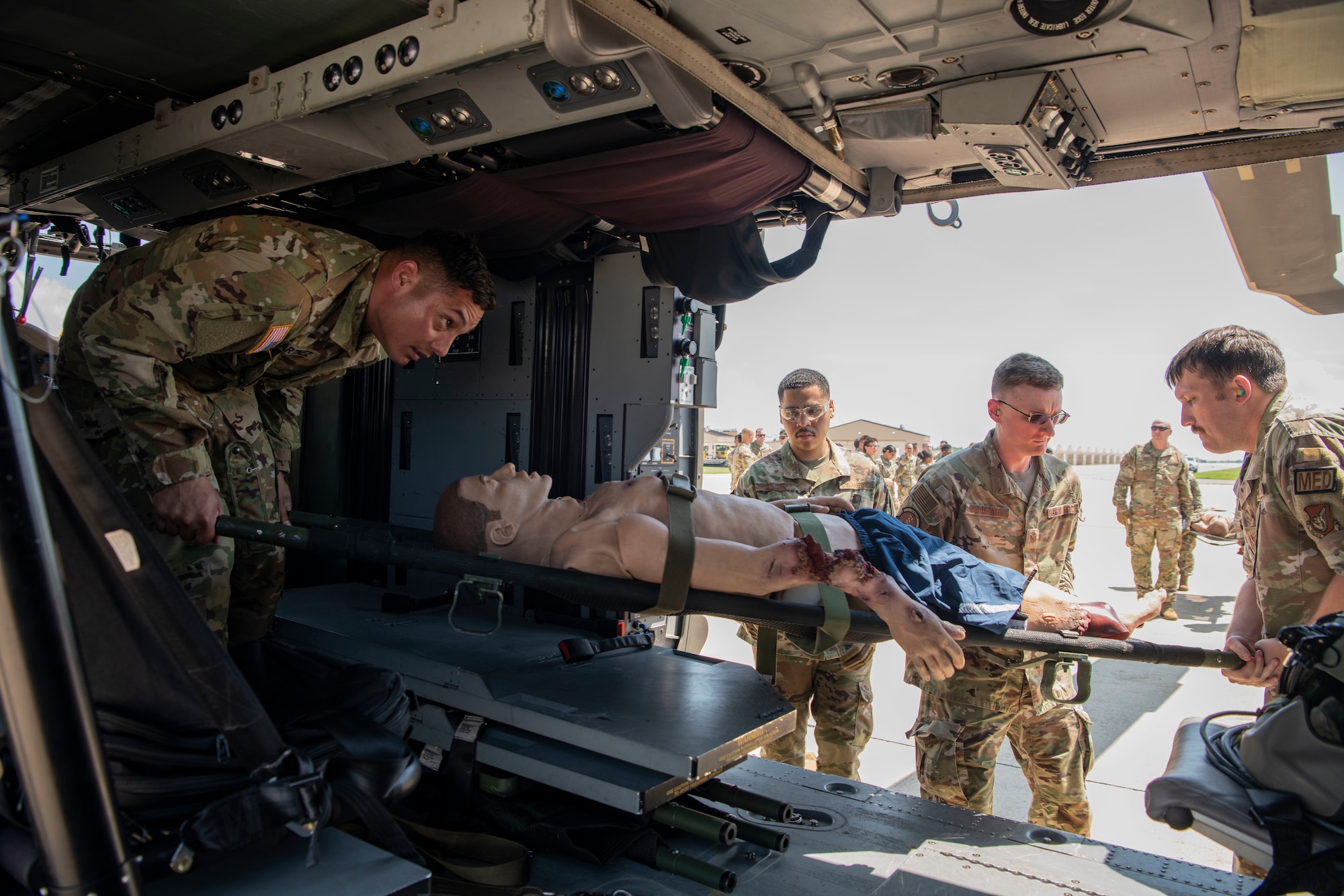 U.S. Army Sgt. Christian Martinez, 2nd Combat Aviation Brigade Charlie Company 3-2 flight crew chief, helps Airmen with the 8th Medical Group load a simulated casualty into a UH-60 Black Hawk during a training event at Kunsan Air Base, Republic of Korea, Aug. 18, 2022. The 8th MDG is devoted to optimizing the installation’s readiness in preparation of follow-on forces. (U.S. Air Force photo by Staff Sgt. Sadie Colbert)