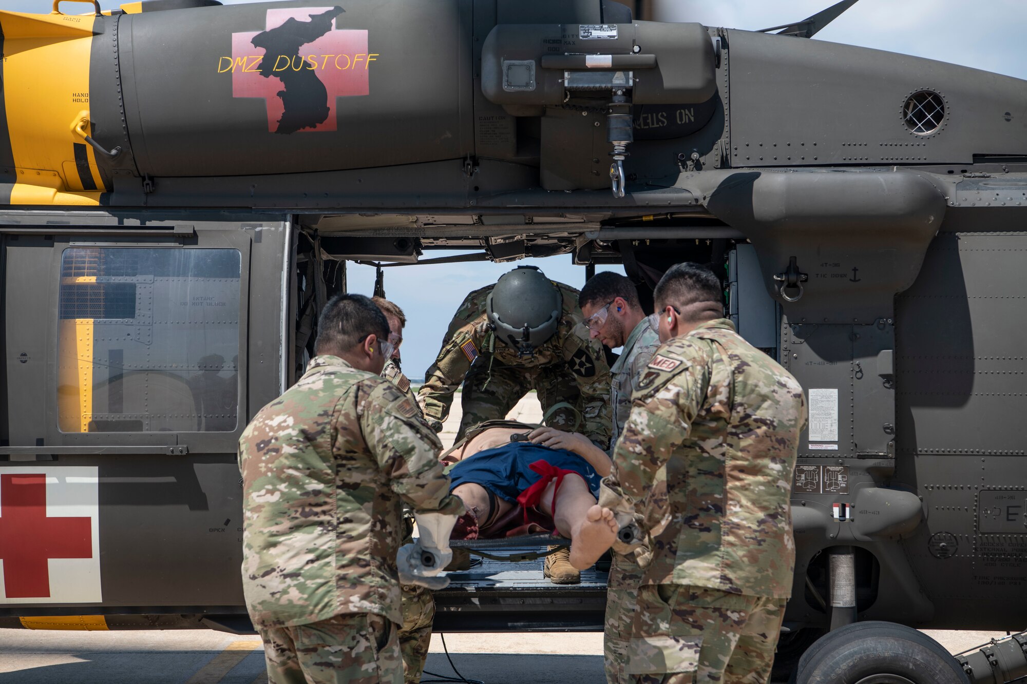 U.S. Army Sgt. Christian Martinez, center, 2nd Combat Aviation Brigade Charlie Company 3-2 flight crew chief, helps Airmen with the 8th Medical Group load a simulated casualty into a UH-60 Black Hawk during a training event at Kunsan Air Base, Republic of Korea, Aug. 18, 2022. The 8th MDG is devoted to optimizing the installation’s readiness in preparation of follow-on forces. (U.S. Air Force photo by Staff Sgt. Sadie Colbert)