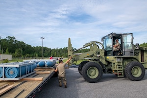 U.S. Air Force Staff Sgt. Huy Dinh, 125th Munitions Flight line delivery production supervisor, removes a tarp cover unveiling training munitions that arrived at the 125th Fighter Wing, Florida Air National Guard, on Aug. 24, 2022. The inert general purpose bombs, called the MK-84s, are the first air-to-ground training assets to arrive for the new F-35 Lightning II mission. (U.S. Air National Guard photo by Tech Sgt. Chelsea Smith)
