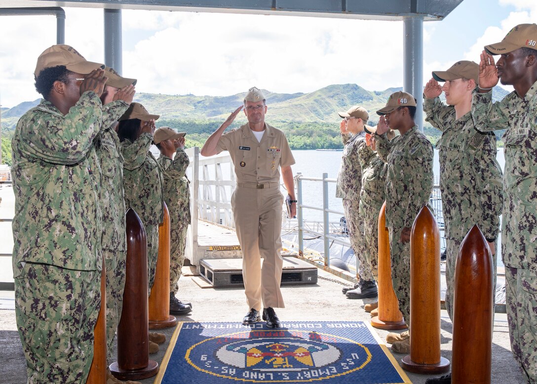 Vice Admiral Darse Crandall, Judge Advocate General of the Navy, center, salutes as he walks past side boys aboard the submarine tender USS Emory S. Land (AS 39).