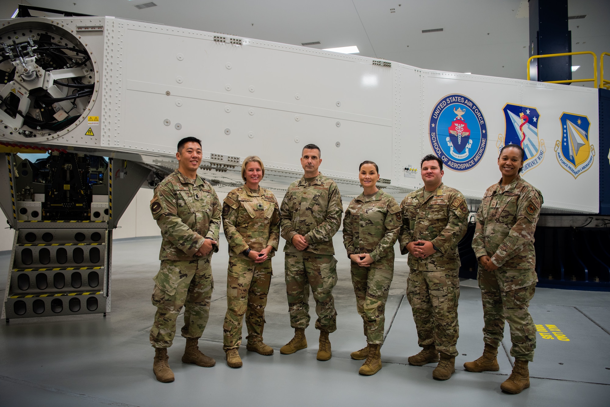 Six people pose for the camera standing in front of the centrifuge.