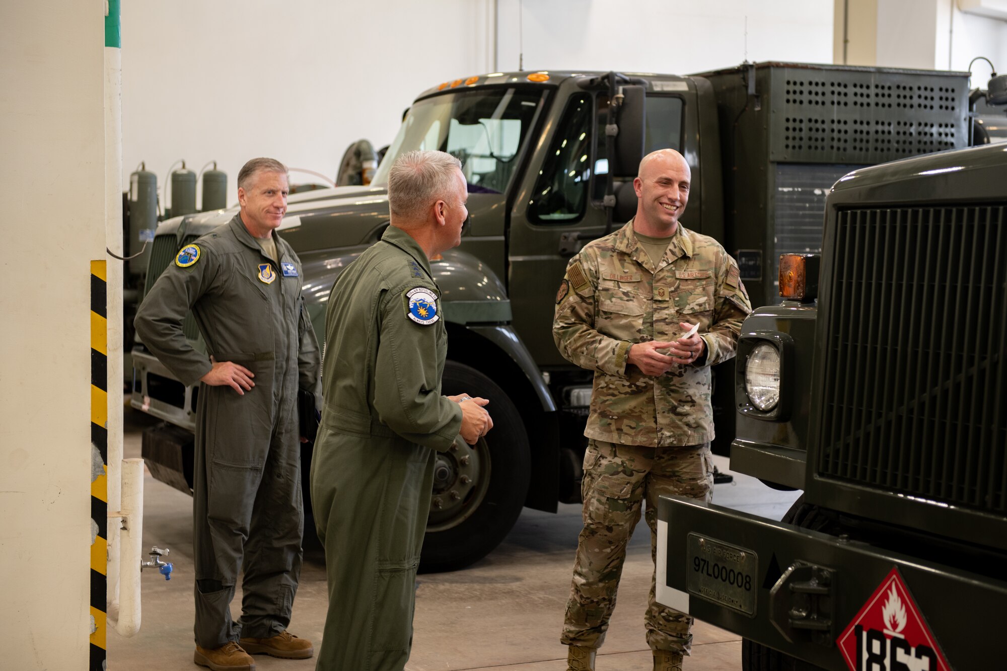 A USAF general meets with Airmen in a mechanic shop where trucks are parked