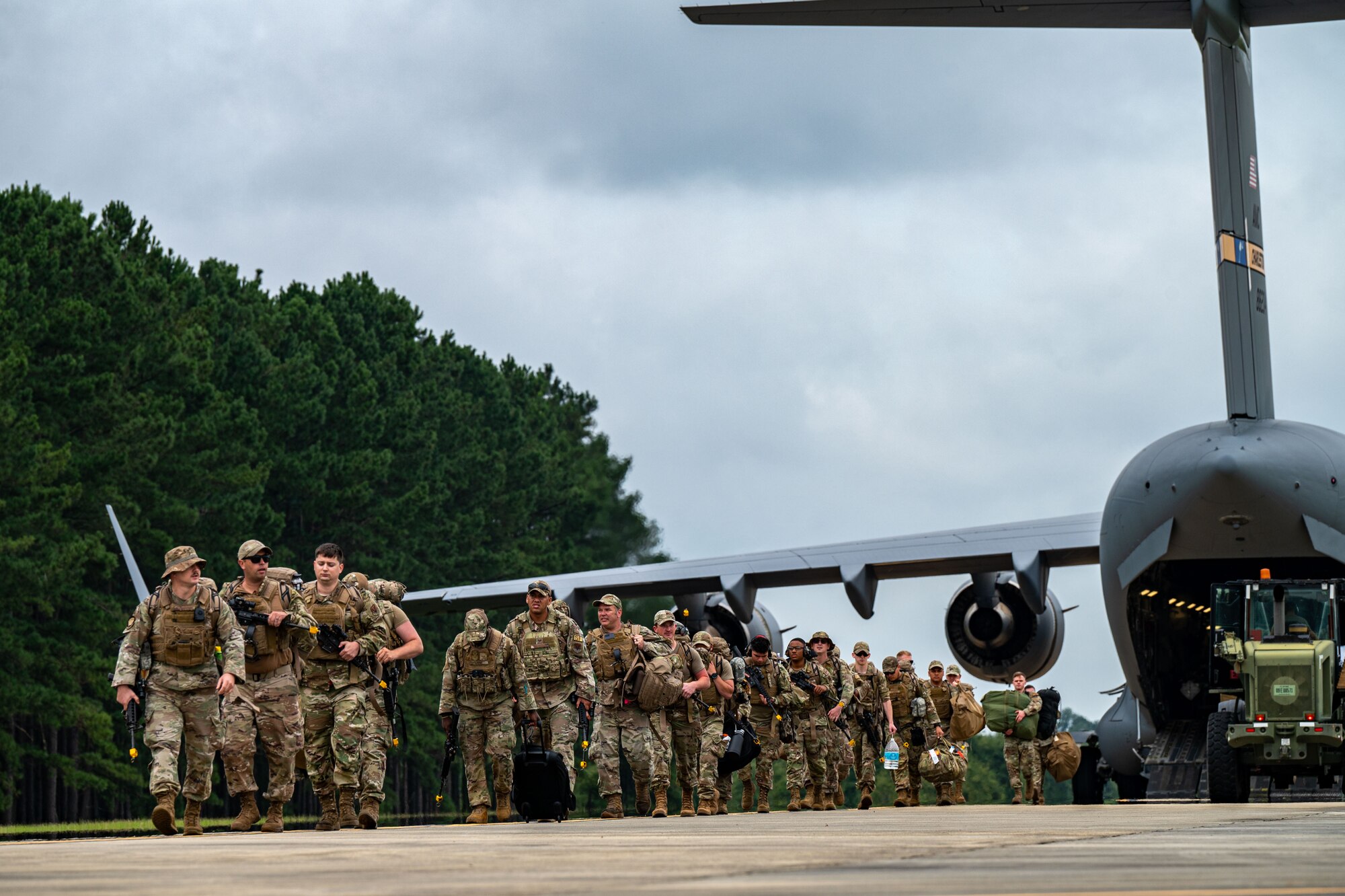 A photo of Airmen walking in a line out of the back of a plane.