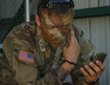 A Soldier from the Headquarters and Headquarters Company, 1st Battalion, 110th Infantry Regiment, 2nd Infantry Brigade Combat Team, applies camouflage before the scout Soldiers move onto their training mission at Fort Indiantown Gap, Pa., on August 3, 2022. The scout Soldiers developed their abilities to communicate and asses as they moved into the woods on their mission (U.S Army photo by Sgt. 1st Class Matthew Keeler)