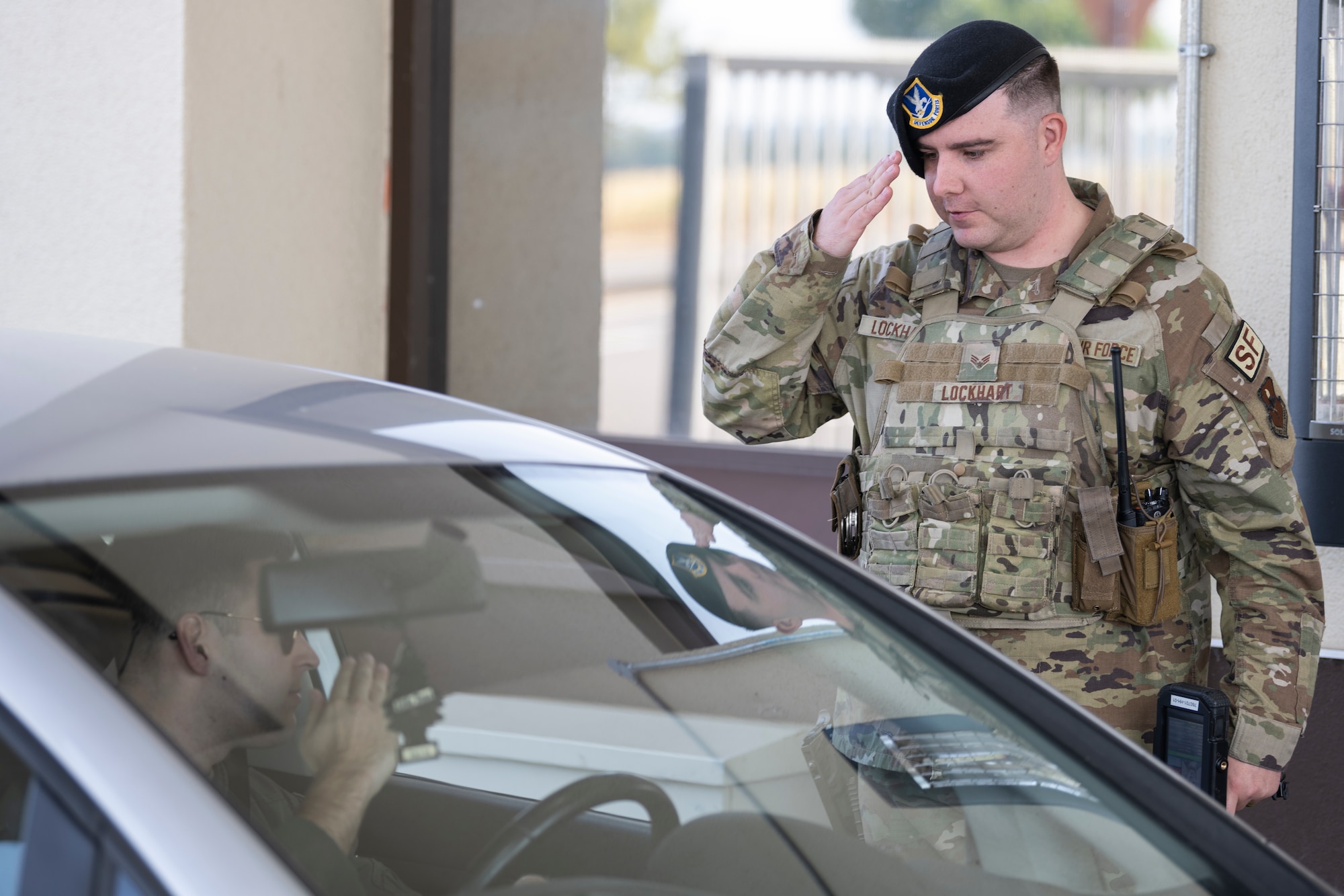 Airmen salutes officer entering gate.