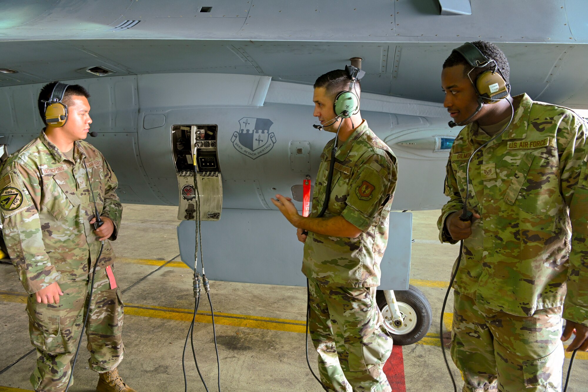 3 airmen talking over headsets at a jet