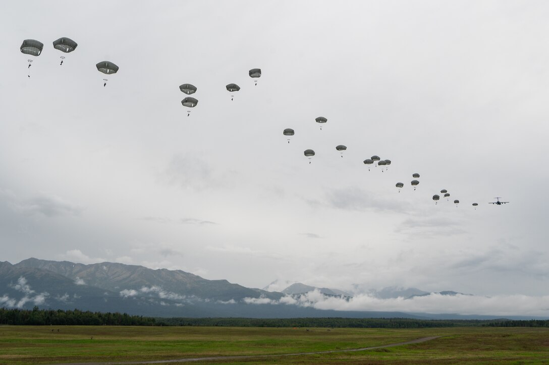Soldiers descend using parachutes.