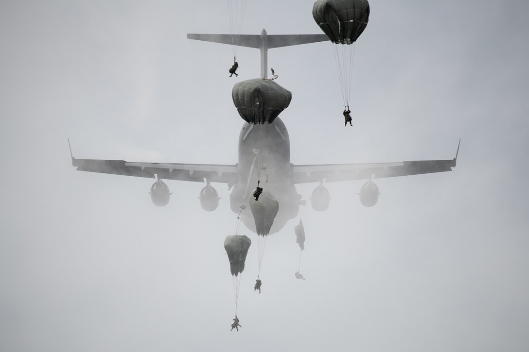 Paratroopers leap from a C-17 aircraft.