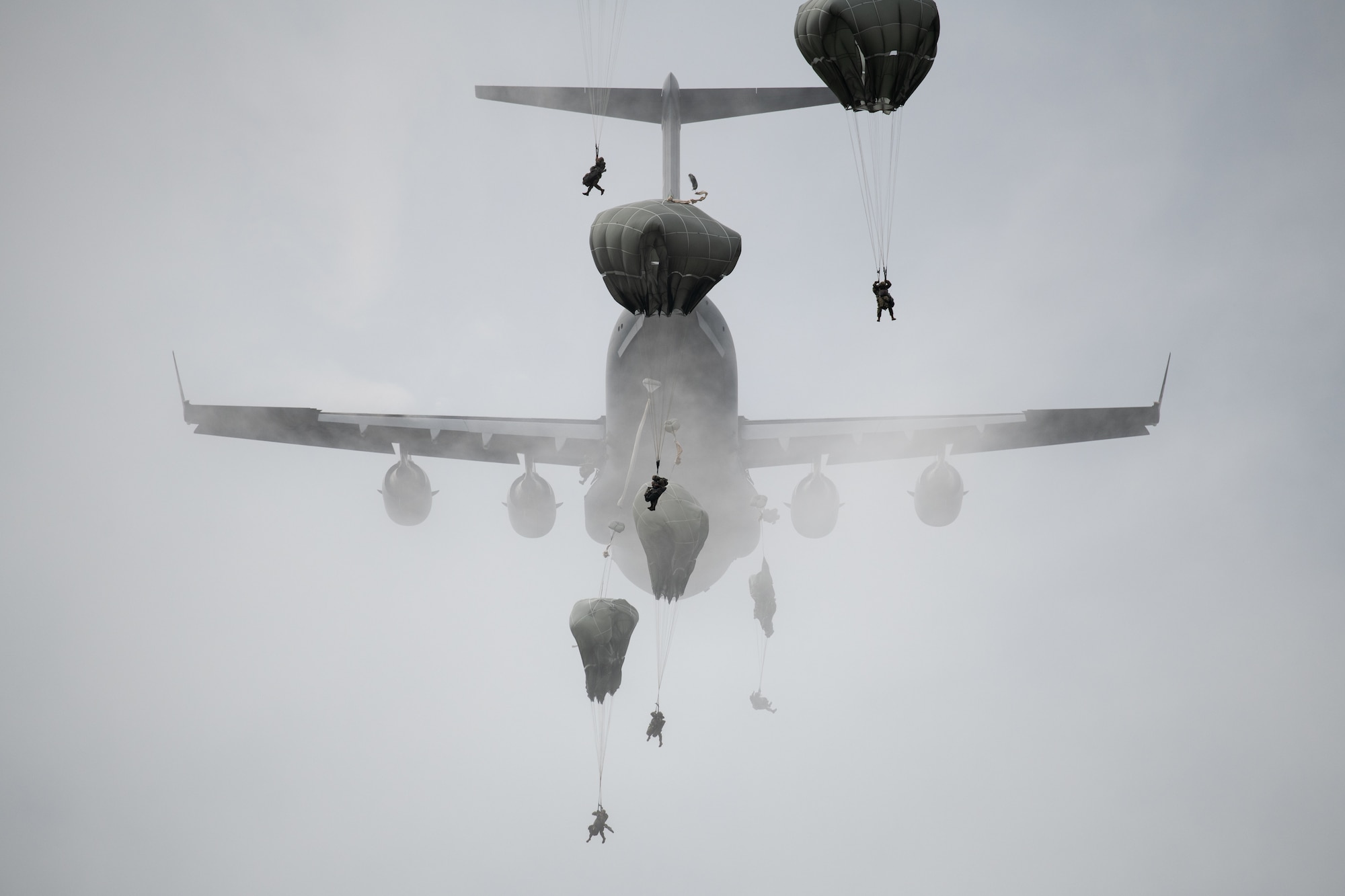 Paratroopers leap from a C-17 aircraft.
