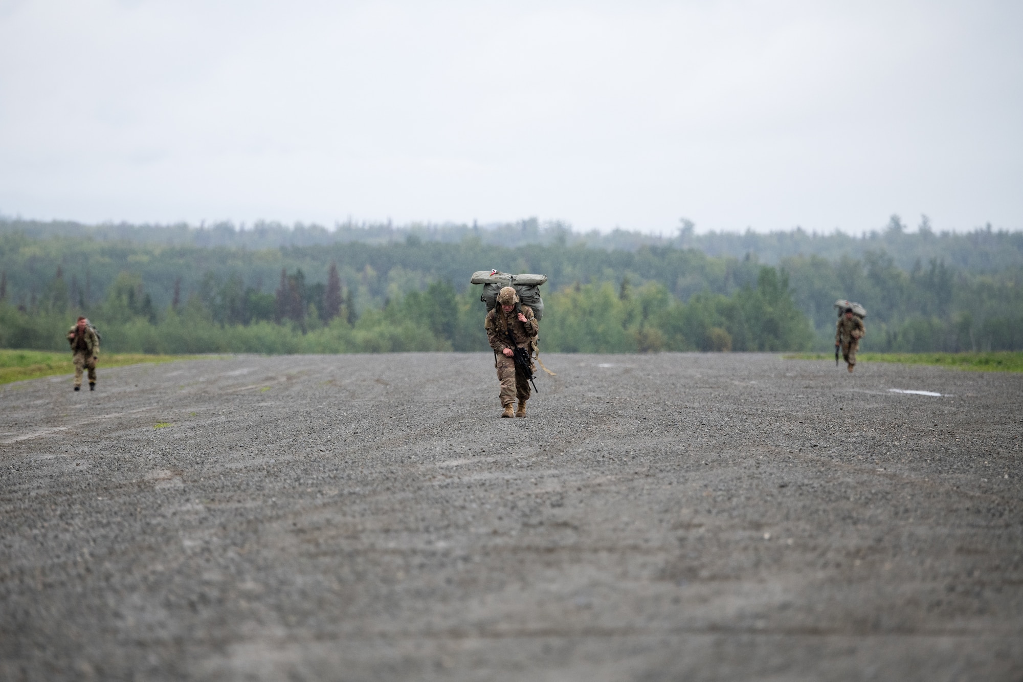 Soldiers walk down a gravel flight line.