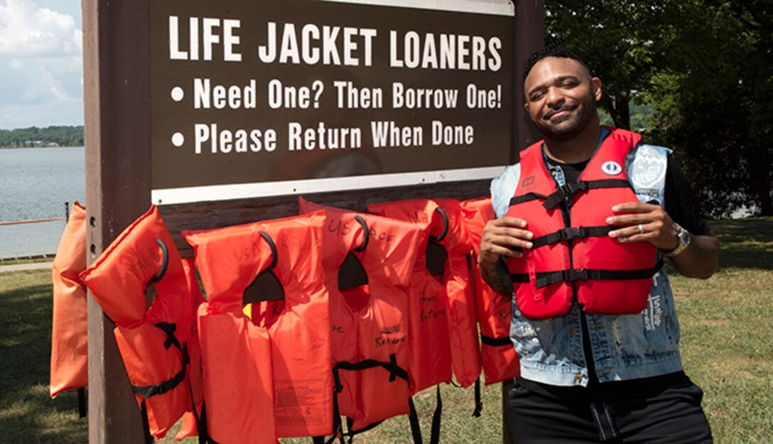 The Artist Muneer Gonsalves poses by the Life Jacket Loaner Board at J. Percy Priest Lake’s Cook Recreation Area in Hermitage, Tennessee, Aug. 26, 2022, while partnering with the U.S. Army Corps of Engineers to promote water safety. He encouraged Corps Lakes visitors to wear life jackets, make good decisions, and keep a close eye on children. (USACE Photo by Lee Roberts)
