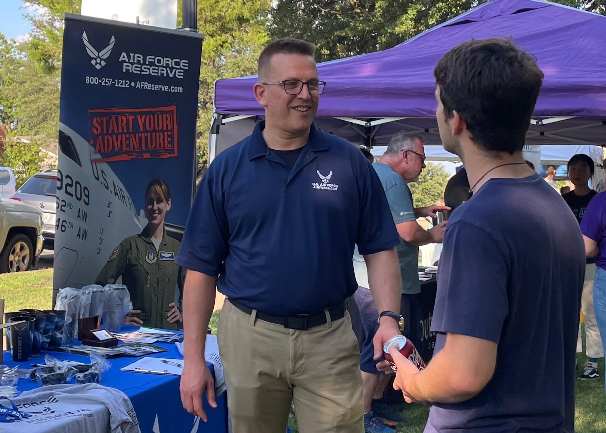 Two people speak by a recruiting table