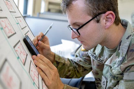 Pvt. 1st Class Samuel Schmelzer, 376th Financial Management Support Unit financial management technician, outlines exercise injects during exercise Diamond Saber at Joint Base McGuire-Dix, New Jersey, Aug. 12, 2022. Established in 2004, Diamond Saber is a U.S. Army Reserve-led exercise that trains and evaluates Soldiers and joint partners on warfighting functions such as funding the force, payment support, disbursing operations, accounting, fiscal stewardship, auditability and data analytics. (U.S. Army photo by Mark R. W. Orders-Woempner)