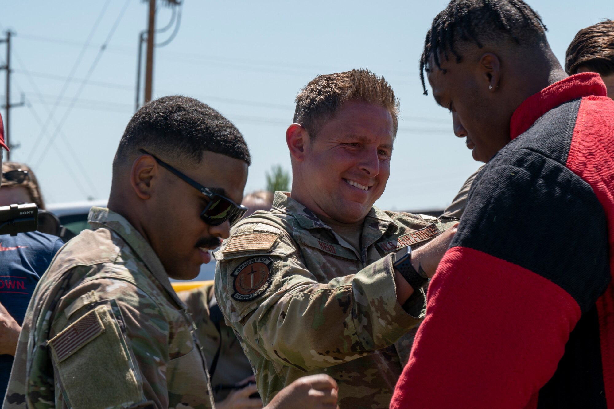 Photo of a man helping another man put on a protective suit.