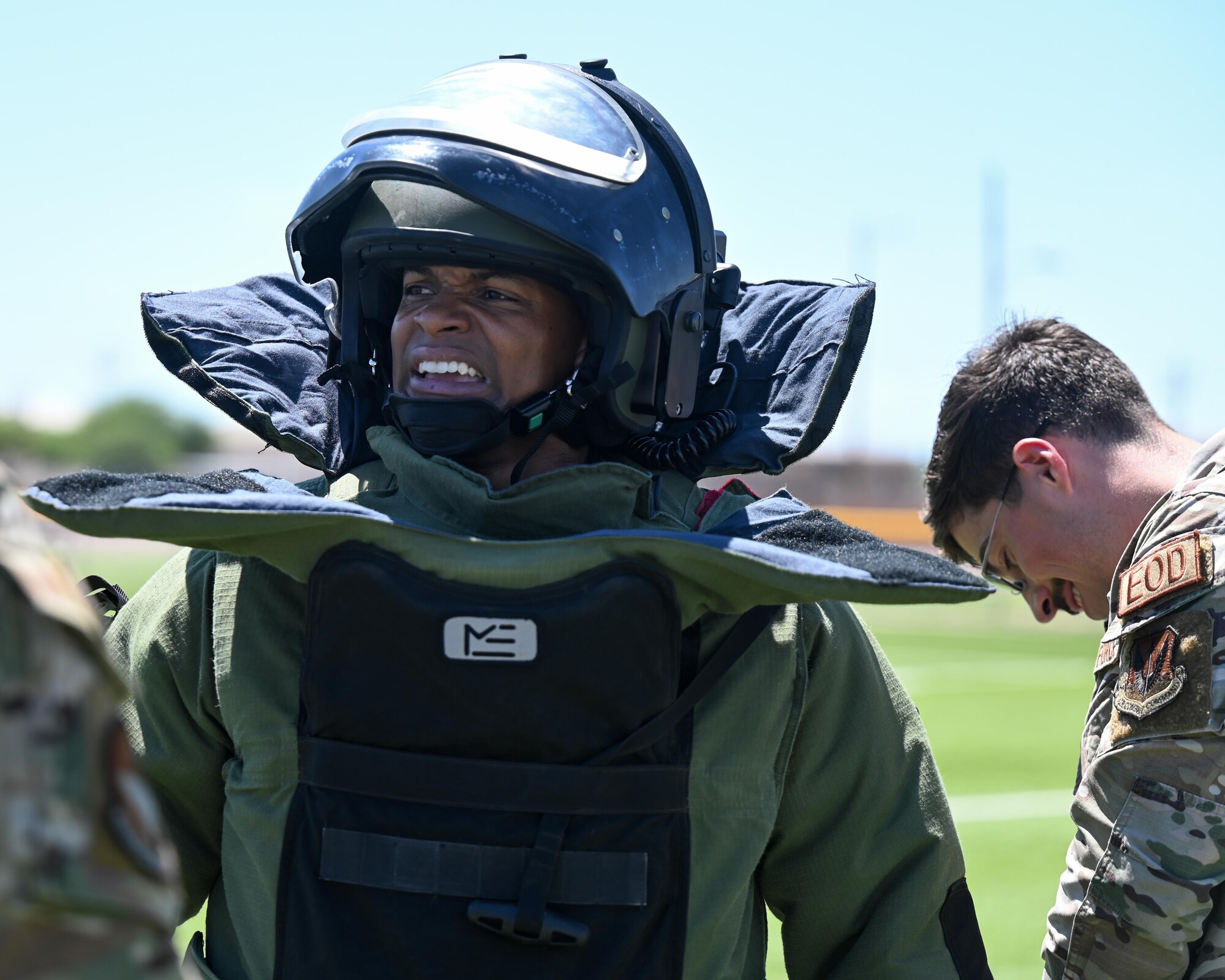 A photo of a man smiling in a bomb suit.