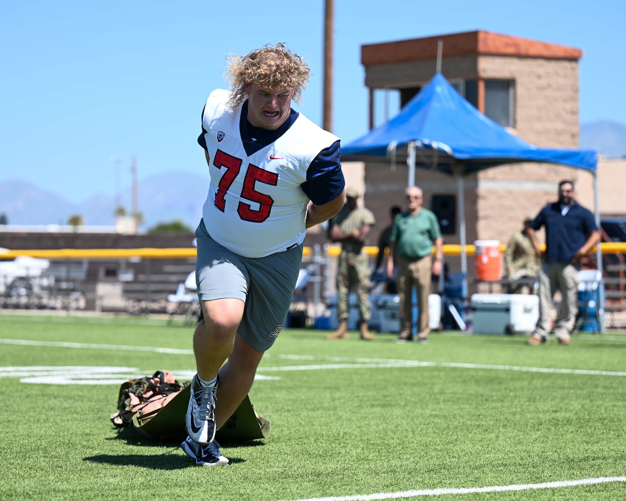 A photo of a football player pulling a sled with a mannequin on it.