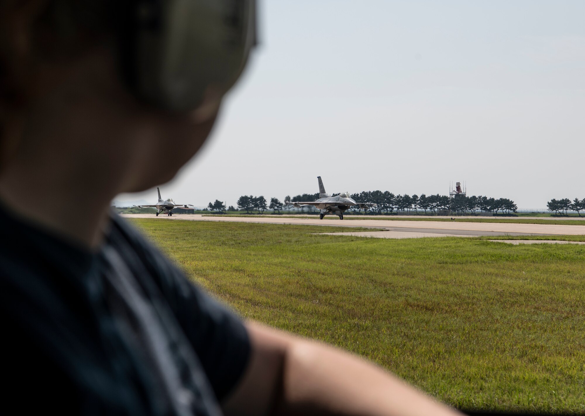 Airman 1st Class Maggie Bennett, 8th Logistics Readiness Squadron fuels distribution operator, waits as F-16 Fighting Falcons taxi at Kunsan Air Base, Republic of Korea, Aug. 26, 2022. The fuels distribution flight is responsible for fueling Kunsan’s F-16 fleet, which continues to support a free and open Indo-Pacific. (U.S. Air Force photo by Staff Sgt. Sadie Colbert)