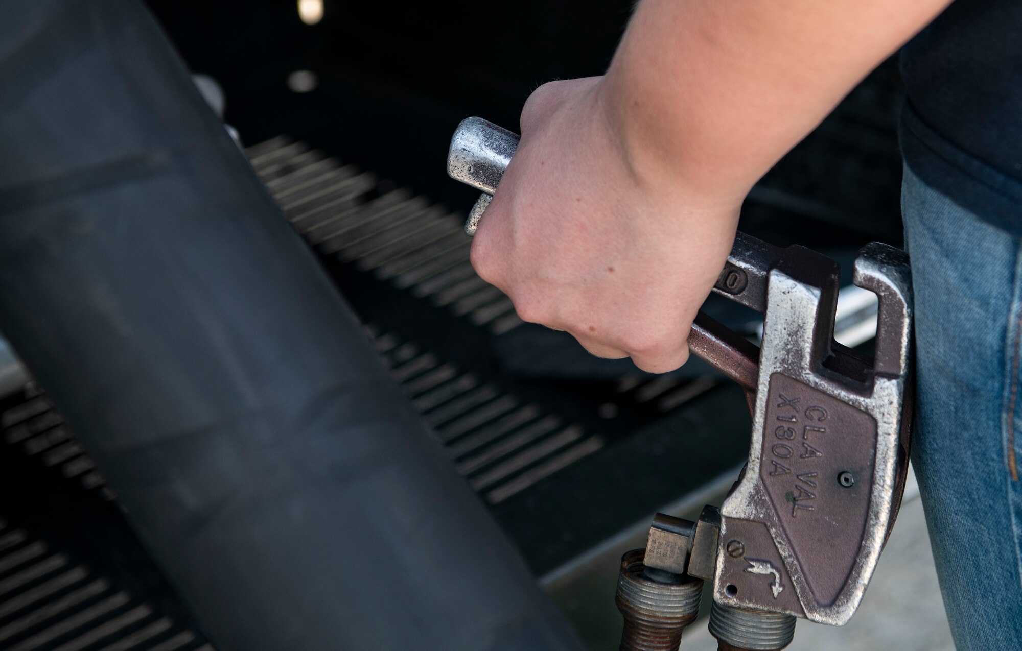 Airman 1st Class Maggie Bennett, 8th Logistics Readiness Squadron fuels distribution operator, squeezes a fuel control handle at Kunsan Air Base, Republic of Korea, Aug. 26, 2022. The fuel hose line allows fuel operators to fuel an aircraft at their parked locations or right before takeoff to help quickly launch jets. (U.S. Air Force photo by Staff Sgt. Sadie Colbert)