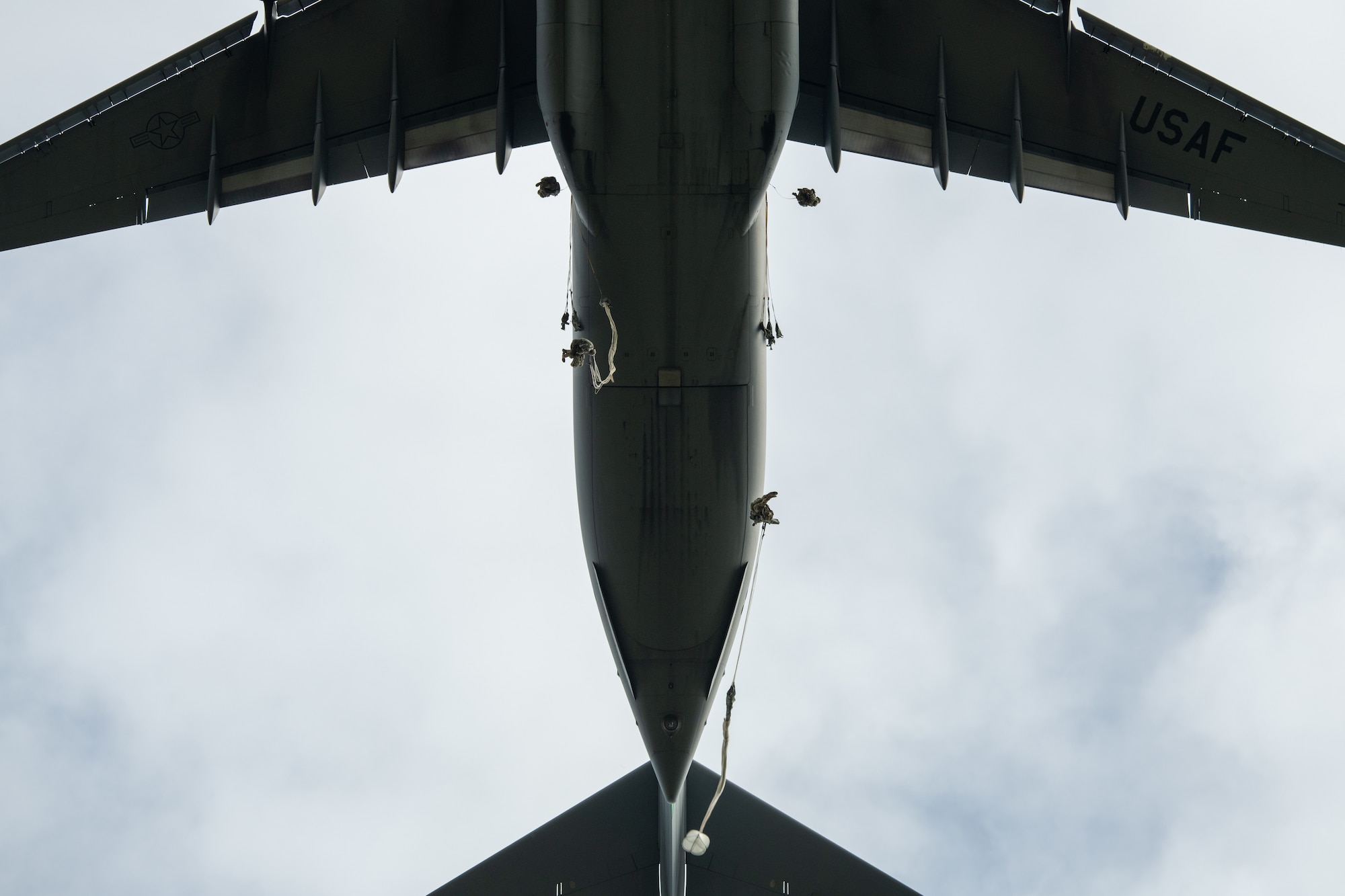 Paratroopers leap from a C-17 aircraft.