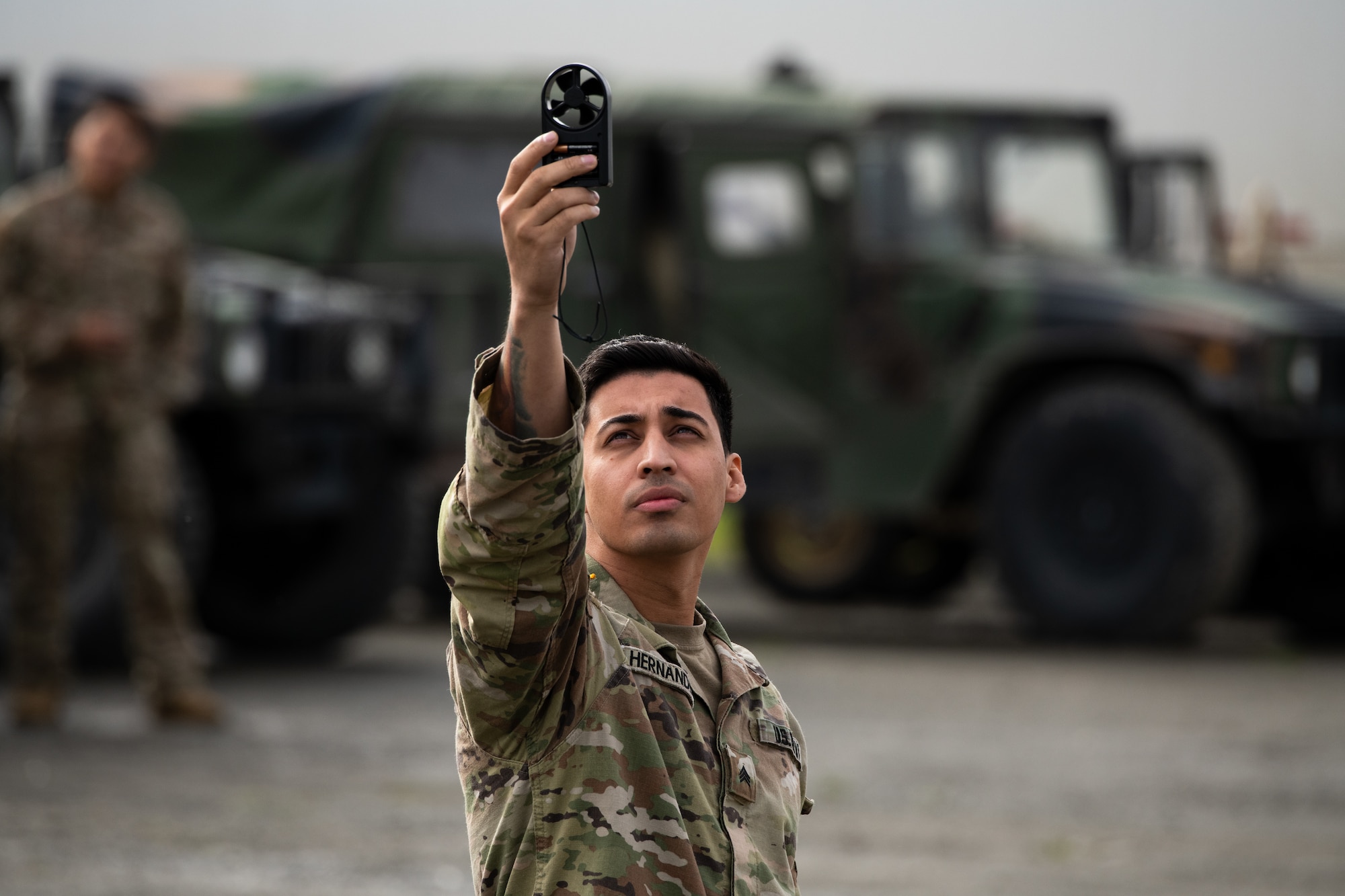 A soldier collects wind speed readings.