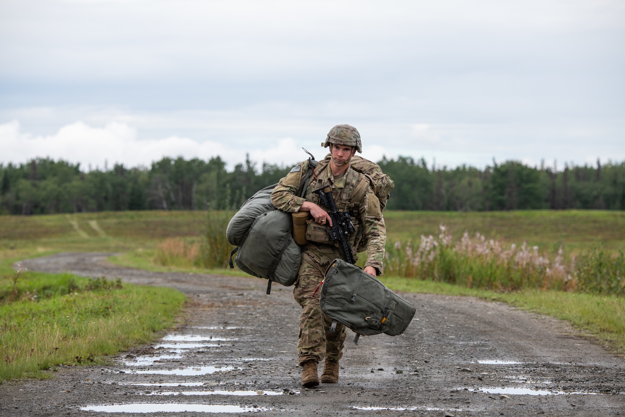 A soldier walks down a muddy road.