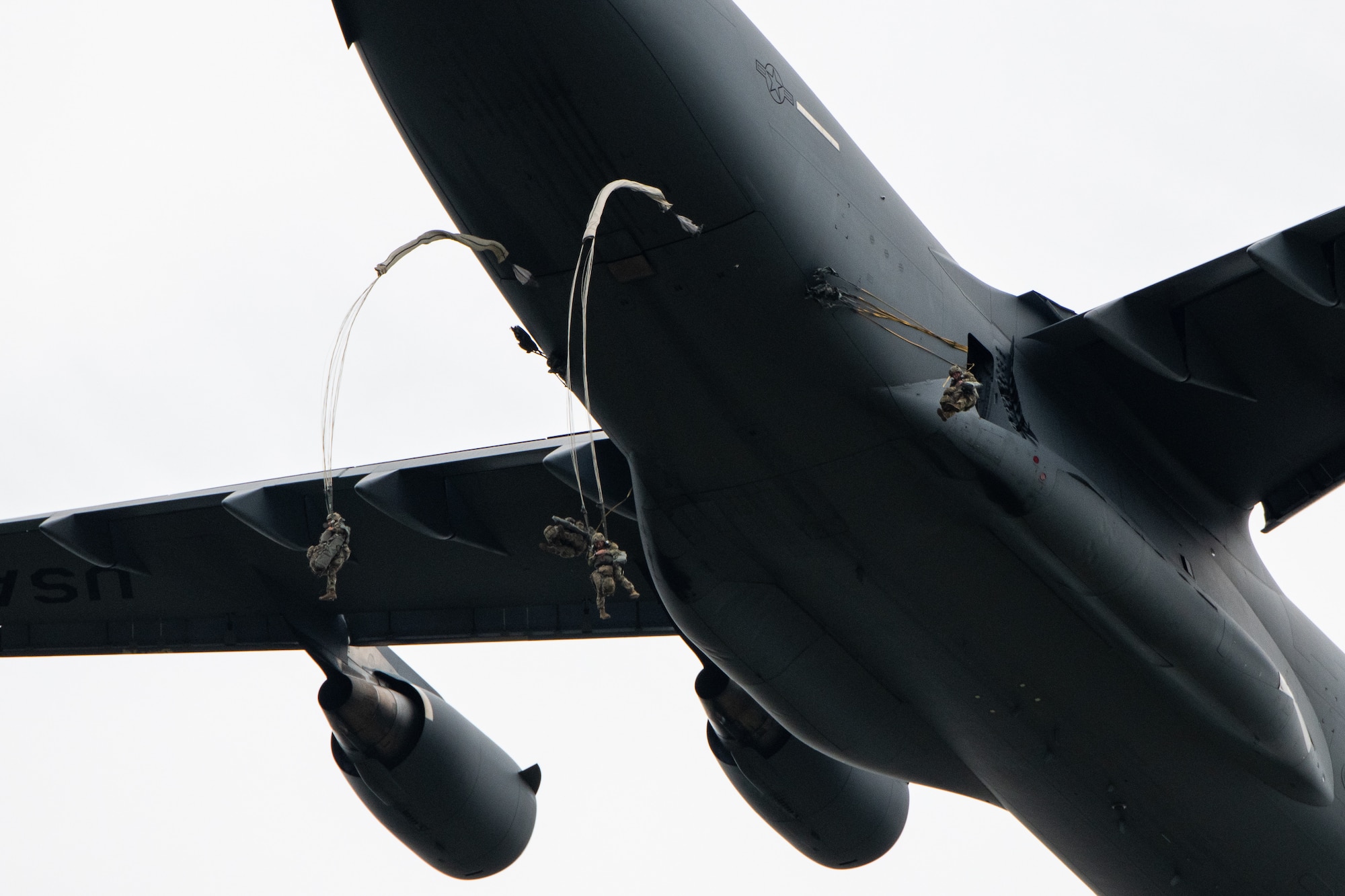 Paratroopers leap from a C-17 aircraft.