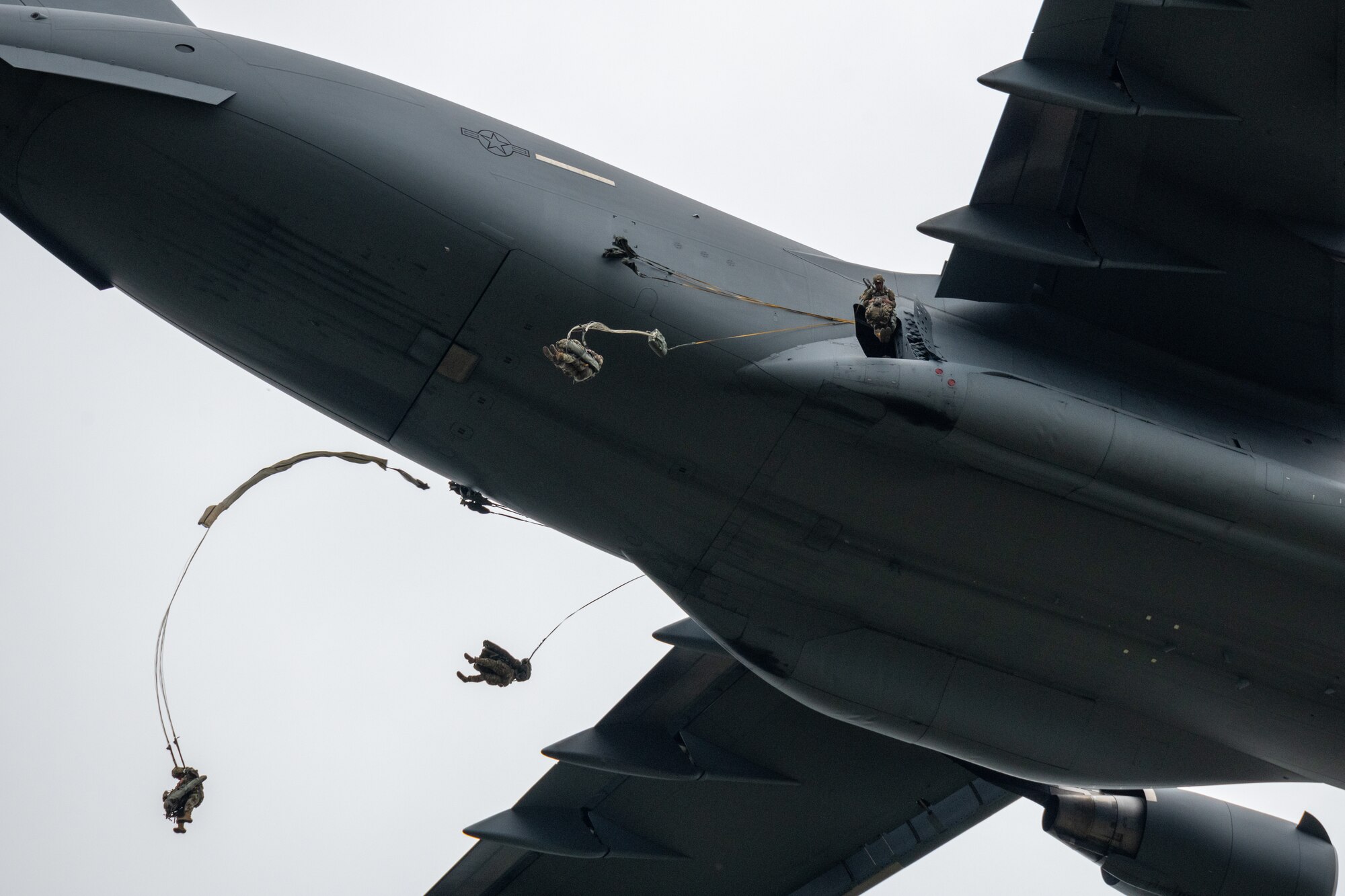 Paratroopers leap from a C-17 aircraft.