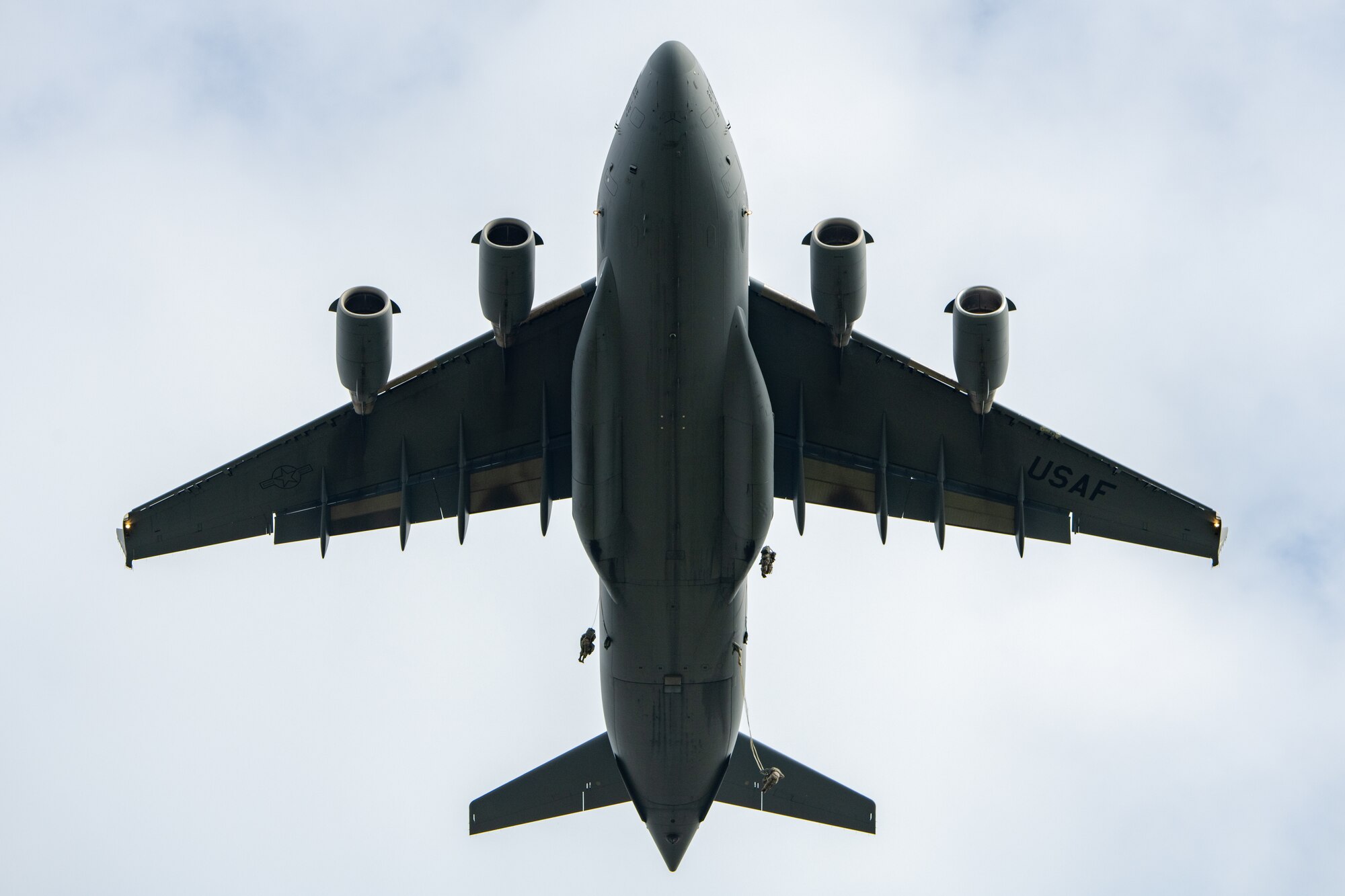 Paratroopers leap from a C-17 aircraft.