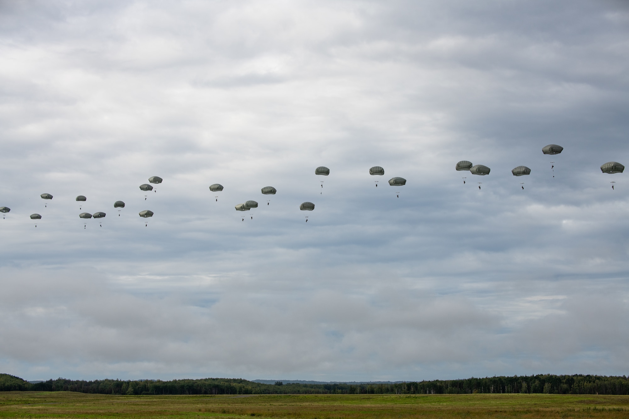 Paratroopers descend with parachutes after airborne operations.