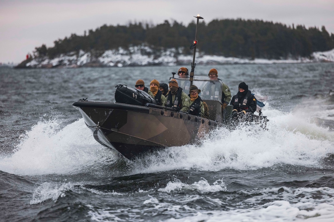 A group of Marines pilot a boat in the water.