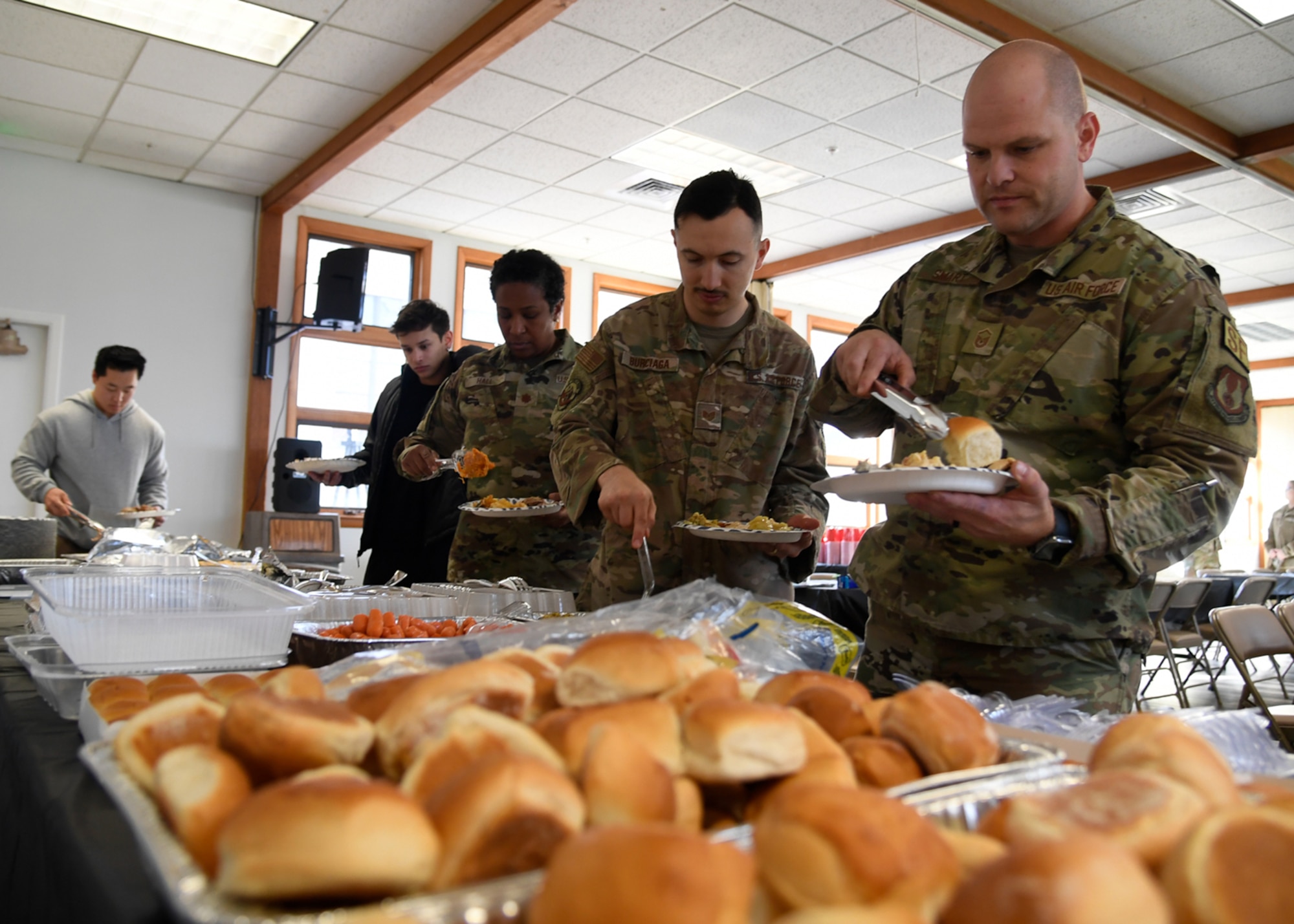 Airmen go through a food line, make plates of food in the chapel annex.