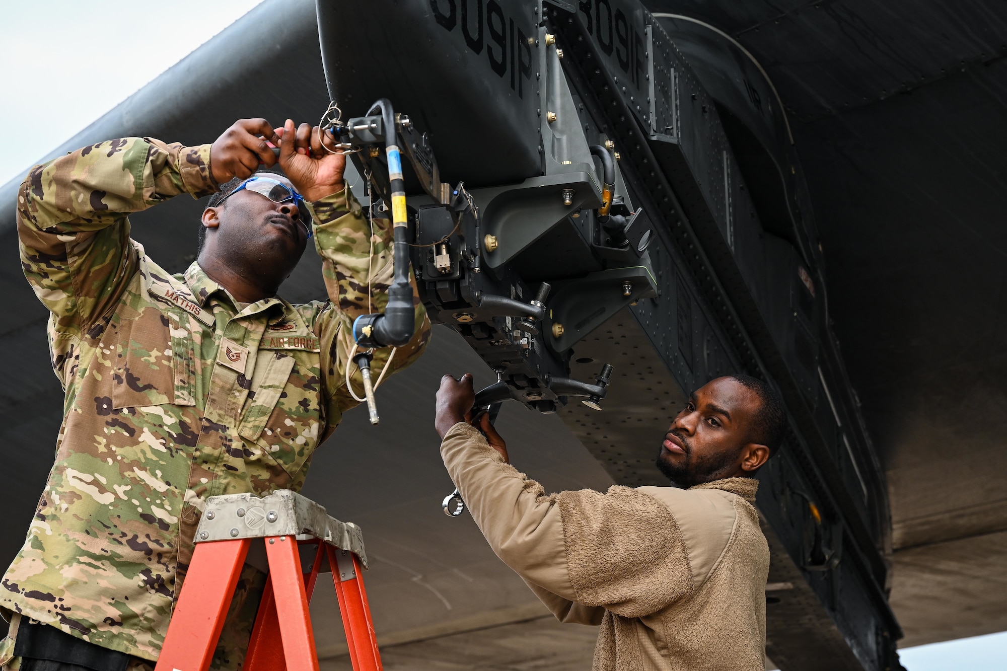 U.S. Air Force Tech Sgt. Charlie Mathis, 2nd Maintenance Group weapons standardization loading standardization crew member, and Tech Sgt. Darrell Stewart, 307th Aircraft Maintenance Squadron loading standardization crew member, prepares a B-52H Stratofortress ejector rack for loading munitions, at Barksdale Air Force Base, Louisiana, Nov. 2, 2022
