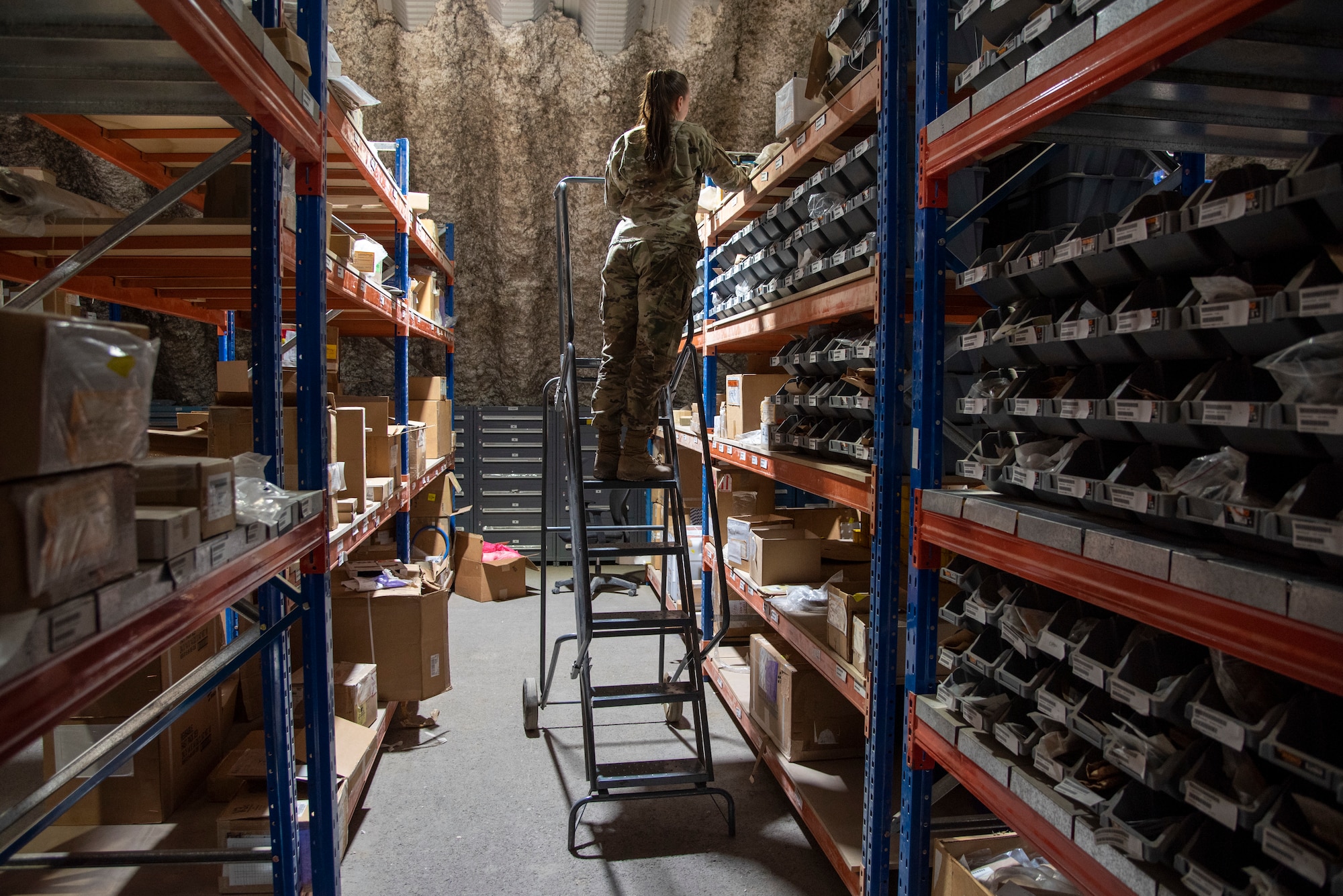Airman 1st Class Kaitlyn Musick, a Journeyman with the 332d Expeditionary Logistics Readiness Squadron, Aircraft Parts Store, retrieves parts in a warehouse at an undisclosed location, Southwest Asia Nov. 11, 2022. The APS provides parts and tools for all maintenance agencies on base. (U.S. Air Force photo by: Tech. Sgt. Jim Bentley)
