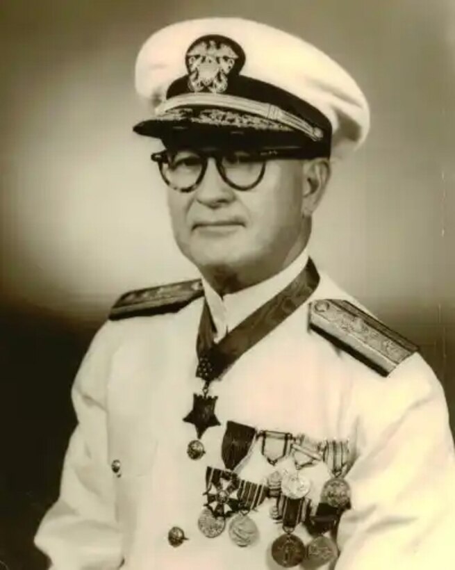 A man wearing several medals on his uniform poses for a photo.