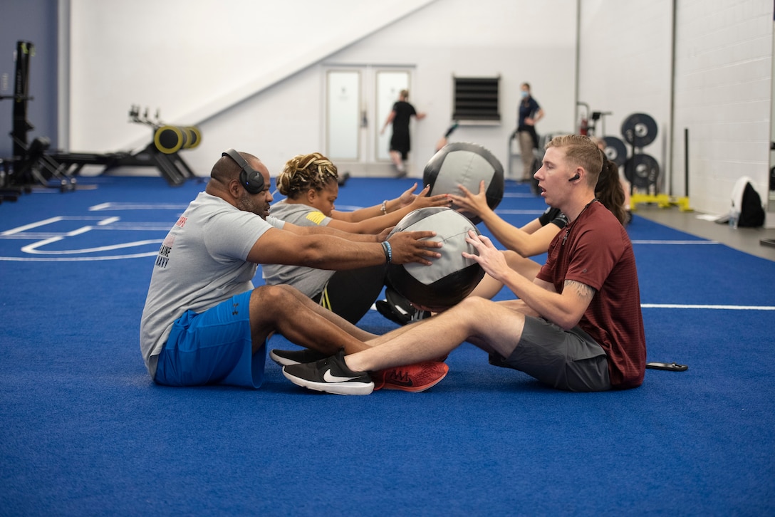 RSMs sit on the floor passing a medicine ball back and forth.