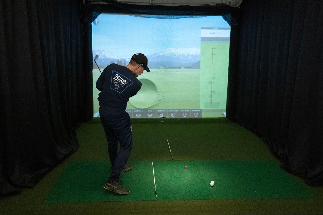 An RSM drives a golf ball into the screen of a golf simulator.