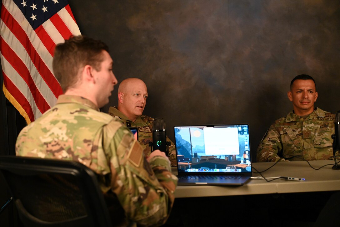 From left, Senior Airman Trenton Jancze, 97th Air Mobility Wing (AMW) public affairs journeyman, Col. Blaine Baker, 97th AMW commander, and Chief Master Sgt. Cesar Flores, 97th AMW command chief, listen to Gail Hargis, 97th AMW chief of protocol, while recording the Debrief podcast at Altus Air Force Base, Oklahoma, Nov. 29, 2022. At the beginning of 2022, the 97th AMW command team created their own podcast called, ‘The Debrief’. (U.S. Air Force photo by Airman 1st Class Kari Degraffenreed)