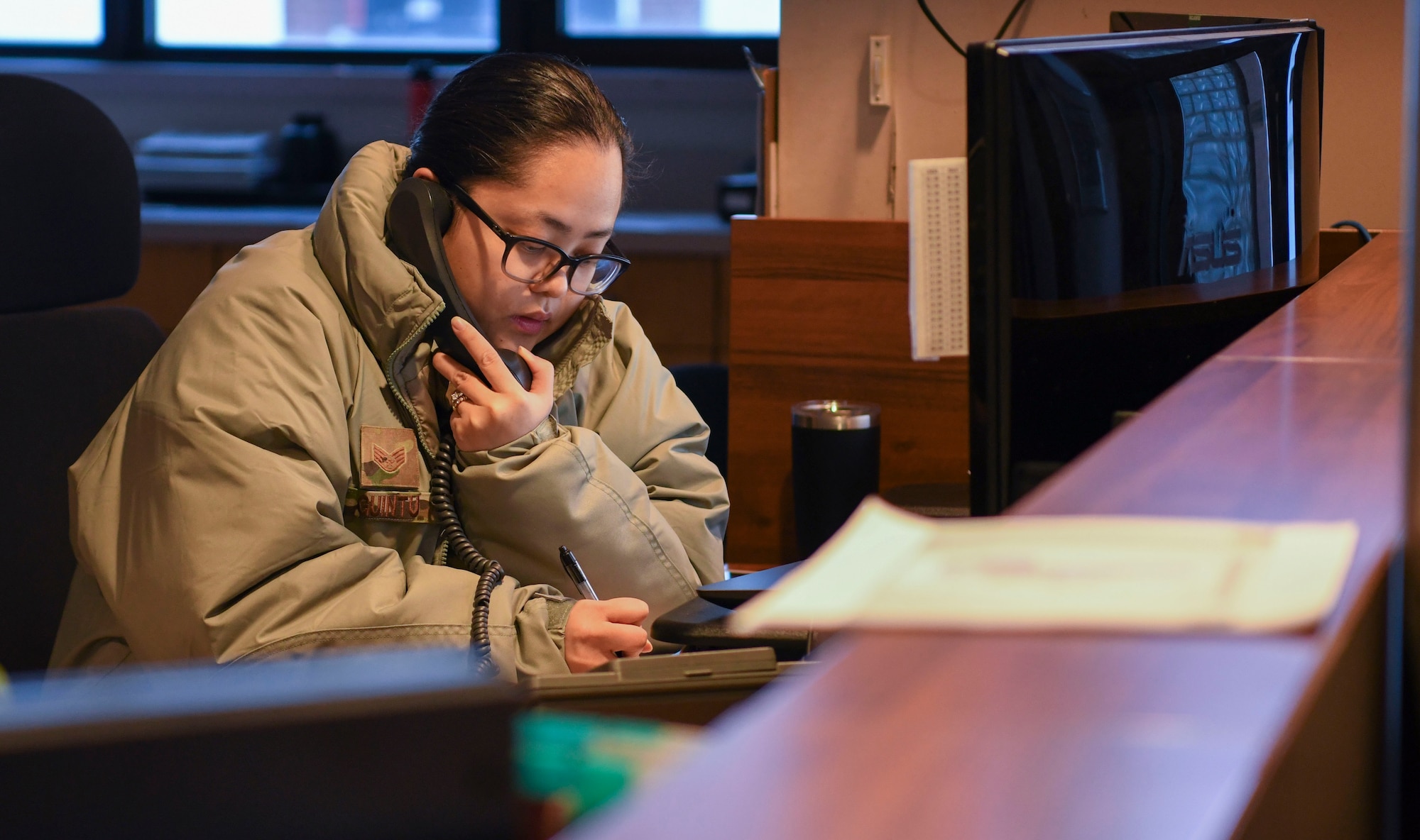 A woman in a military uniform talks on the phone.