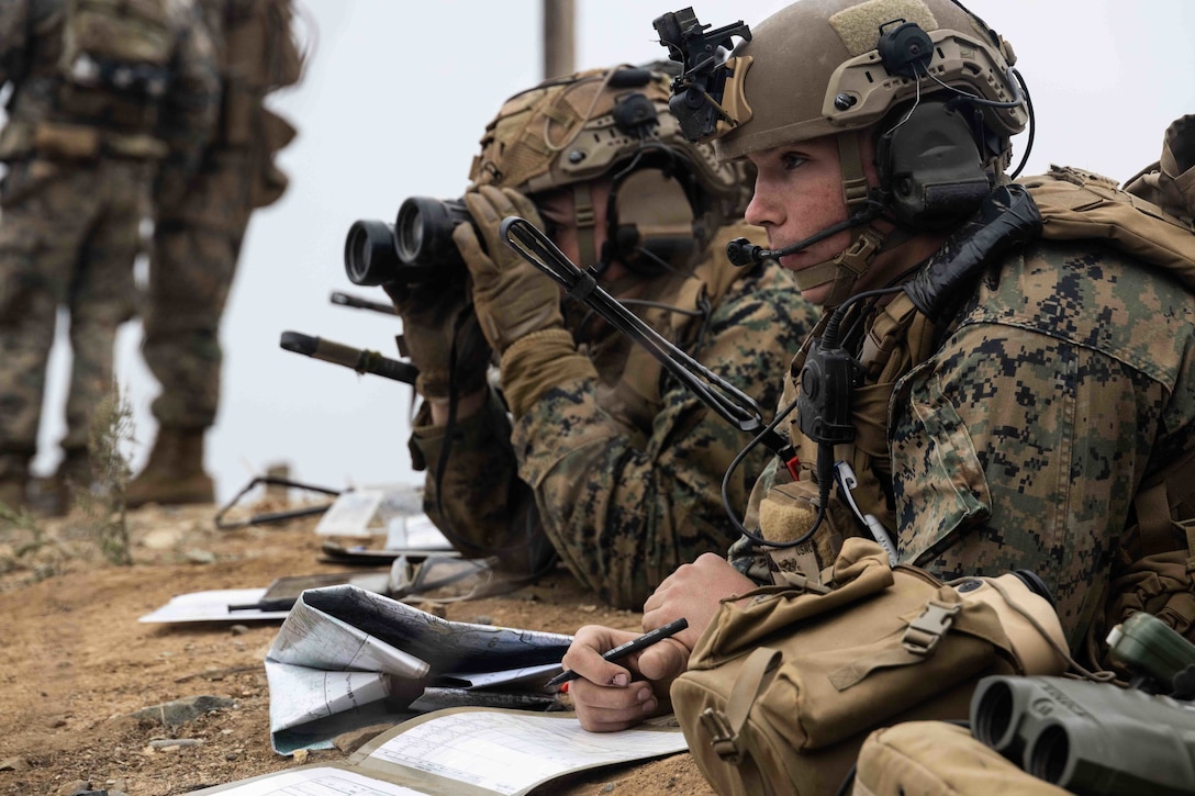 U.S. Marine Corps Cpl. Michael Brown, a radio operator with 3d Battalion, 7th Marine Regiment, 1st Marine Division (1st MARDIV), observes an impact zone during Exercise Steel Knight 22 (SK-22) at Marine Corps Base Camp Pendleton, California, Dec. 9, 2021. SK-22 is a 1st MARDIV-led annual training exercise which enables the Navy-Marine Corps team to operate in a realistic, combined-arms environment to enhance naval warfighting tactics, techniques and procedures. (U.S. Marine Corps photo by Cpl. Cameron Hermanet)