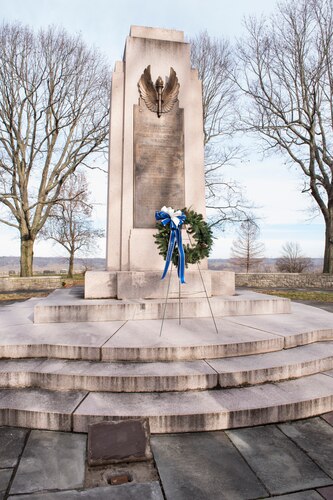 A wreath with a blue and white ribbon lays at the Wright Brothers Memorial.